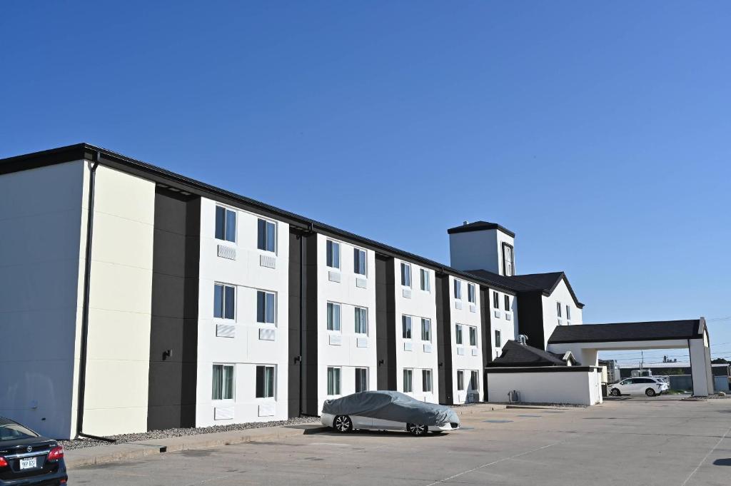 Rodeway Inn في Fremont: مبنى أبيض كبير مع سيارة متوقفة في موقف للسيارات