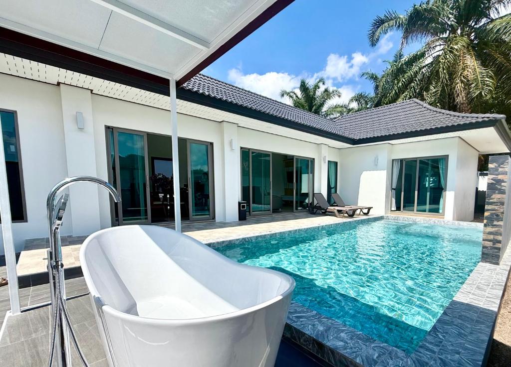 a bath tub sitting next to a swimming pool at Legacy pool villa in Ban Chong Phli