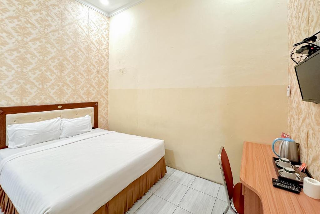 a hotel room with a bed and a television at Perdana Kasih Hotel Pemuda Klaten Mitra RedDoorz in Solo