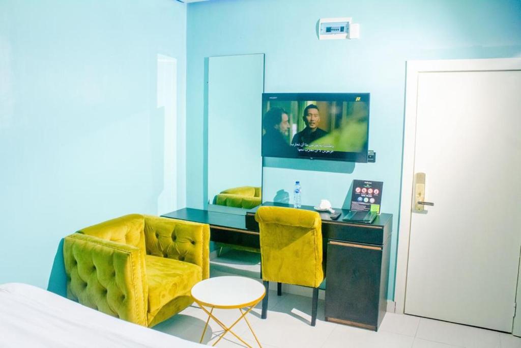 um quarto com uma cama, uma TV e uma cadeira em Paradox Suites Hotel em Lekki