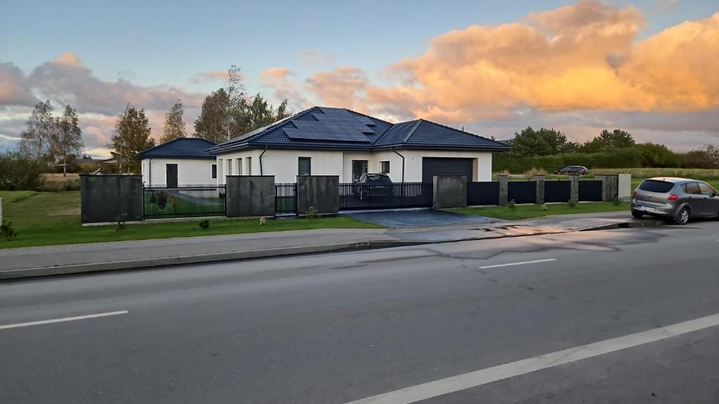 una casa con un'auto parcheggiata sul lato di una strada di Atostogų namelis "Neda" a Palanga