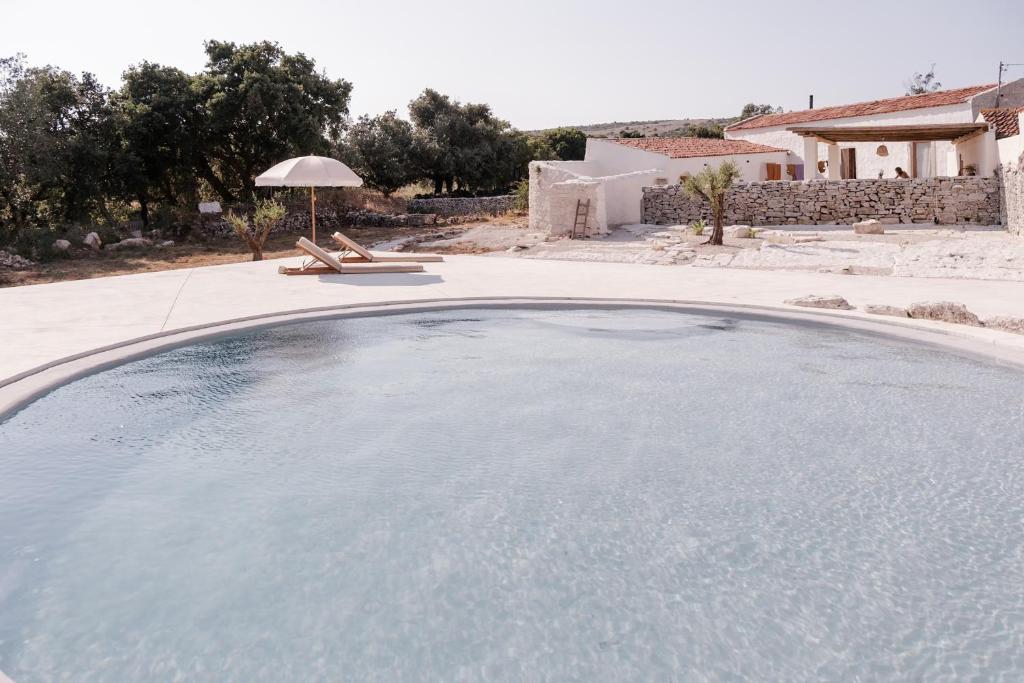 een groot zwembad in een tuin met een parasol bij Casa d'Aire in Porto de Mós