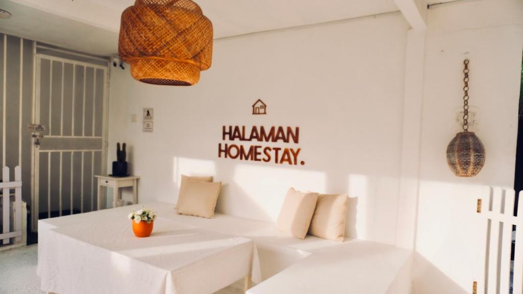 Una habitación blanca con dos mesas blancas y un cartel en la pared. en Halaman Homestay, en Klang