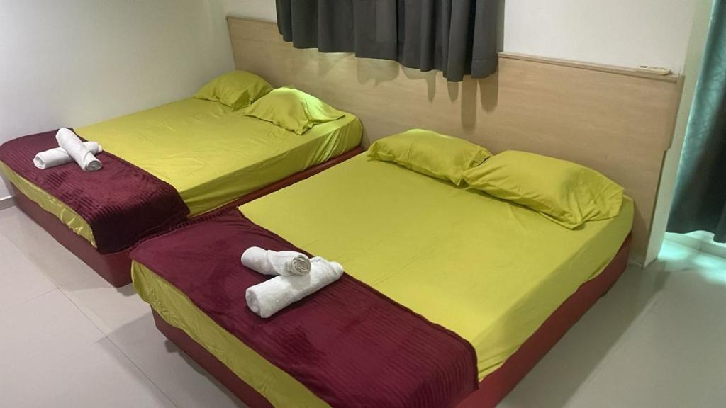 Batu Caves Paradise Hotel في بانيا إليجا: سريرين توأم في غرفة عليها مناشف