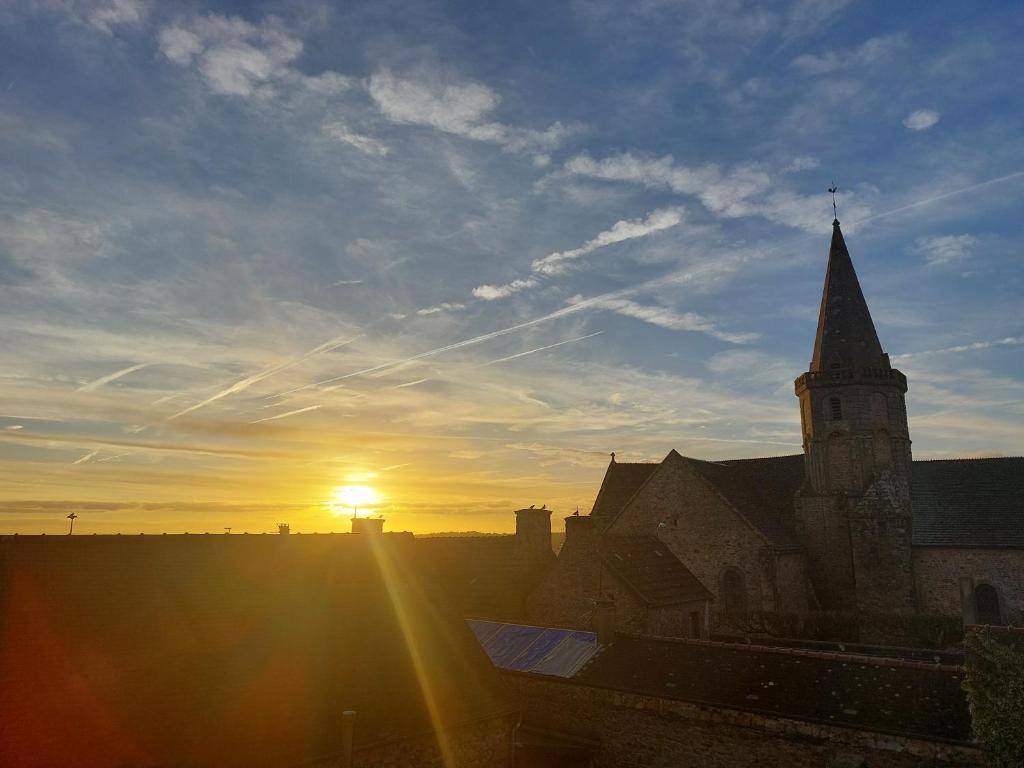 een kerk met de ondergaande zon aan de hemel bij Tranquillitée 2 in Les Pieux