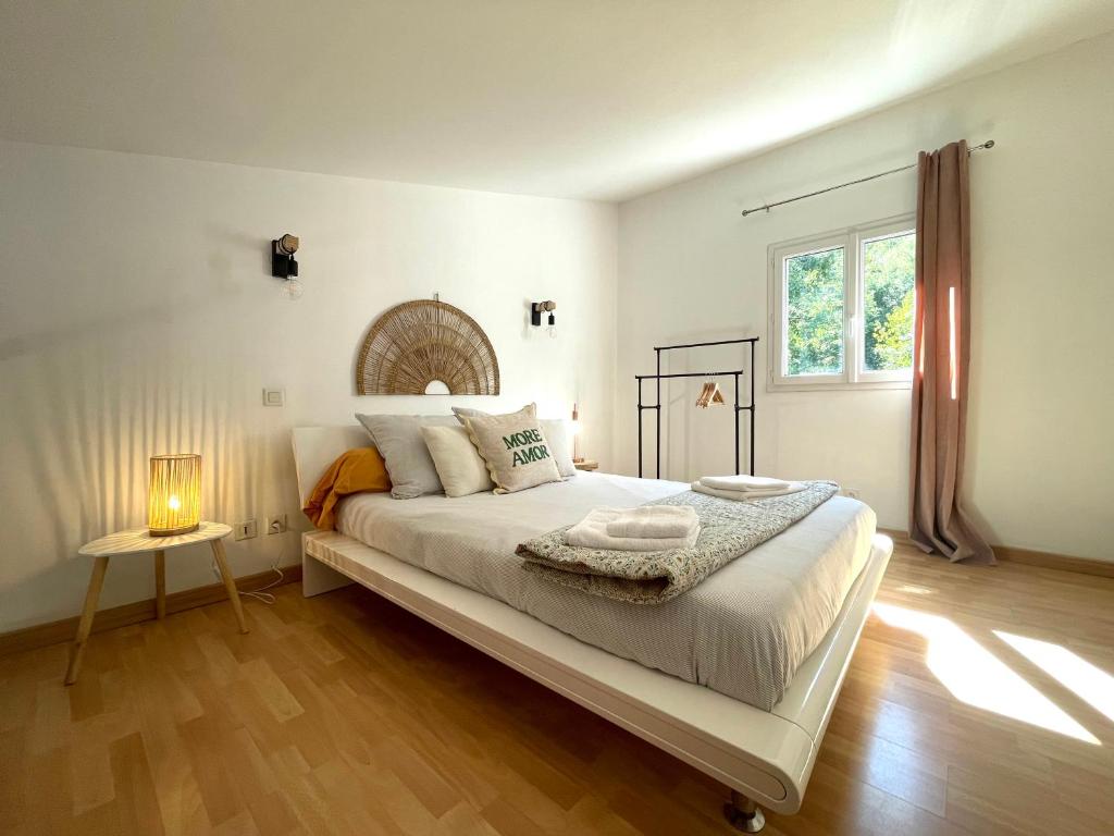 ein weißes Schlafzimmer mit einem großen Bett und einem Fenster in der Unterkunft Charmant Duplex à la campagne in Riventosa
