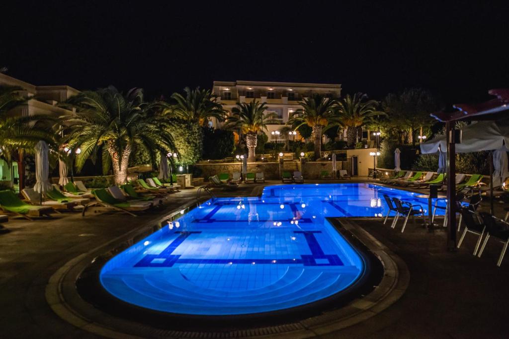 uma piscina à noite com luzes azuis em Crithoni's Paradise Hotel em Alinda