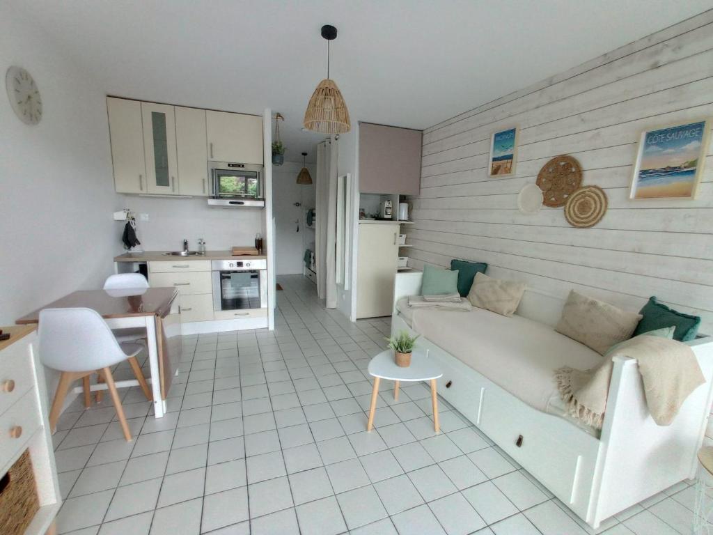 een woonkamer met een bank en een keuken bij Studio l'Oasis - Détente, Jardin & Plage 10 min in Guérande