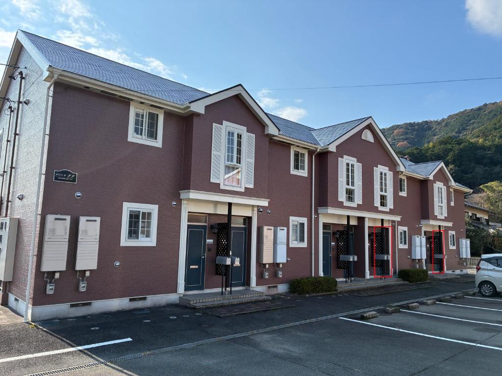 a brown building with white windows in a parking lot at メゾンドyy寺田 アパート1室貸切 素泊まり最大6人宿泊可能 4名様まで同一料金 in Yamaguchi
