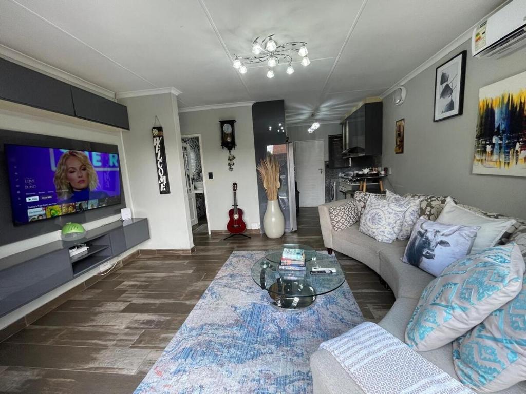 ein Wohnzimmer mit Sofa und Fernseher in der Unterkunft Buenos Manor in Roodepoort