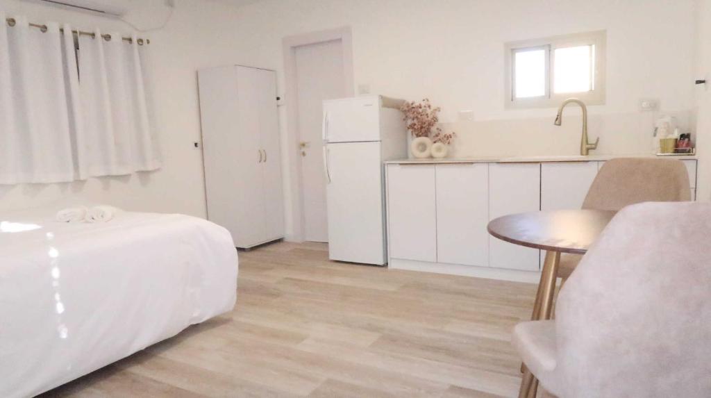 una cucina bianca con tavolo e frigorifero di הצימר של תמר - אורחן מתאים לדתיים a Safed