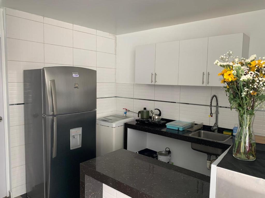 a kitchen with a refrigerator and a vase of flowers at Acogedores pisos en el valle de Mala in Mala
