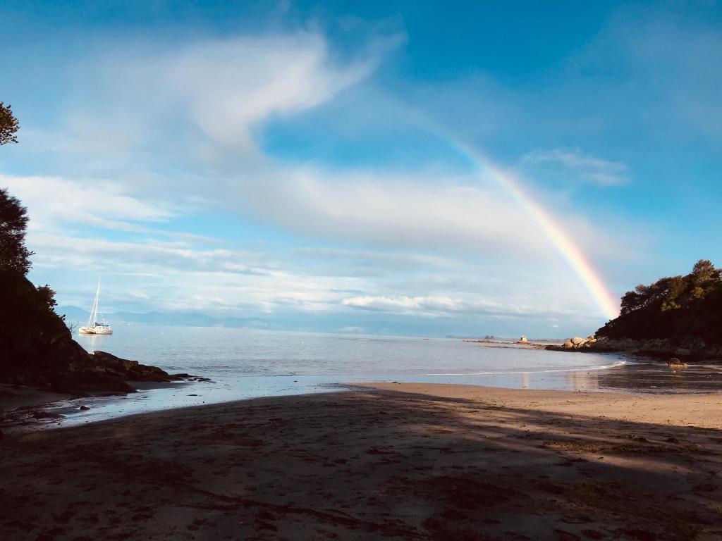 a rainbow over the beach with a boat in the water at Rainbow Lodge in Motueka