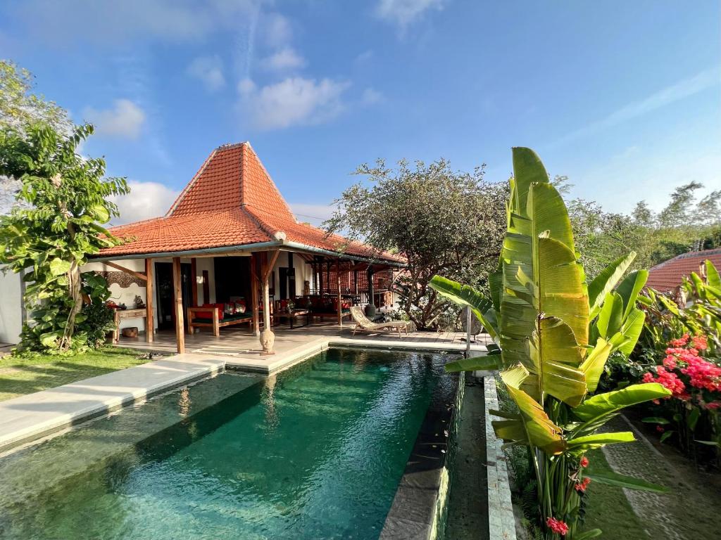a house with a swimming pool in front of it at Joglo Villas Uluwatu - Tropical Oasis in Uluwatu