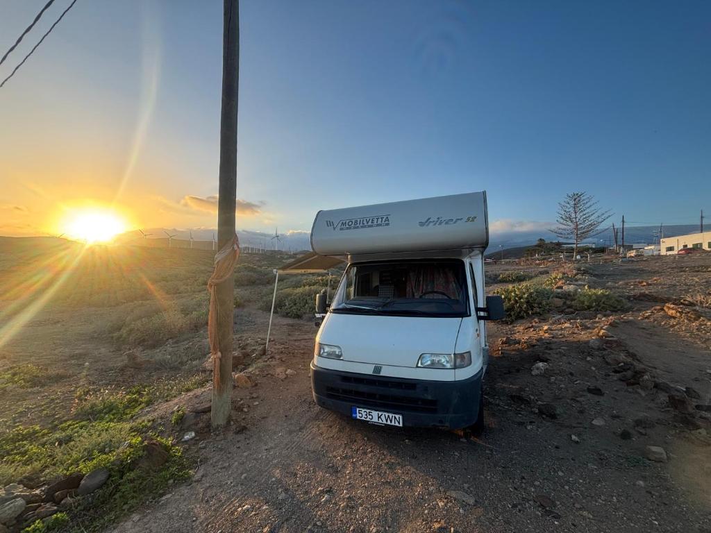 Ein weißer Lieferwagen parkte auf einer unbefestigten Straße im Sonnenuntergang. in der Unterkunft Palmi Caravan in Poris de Abona