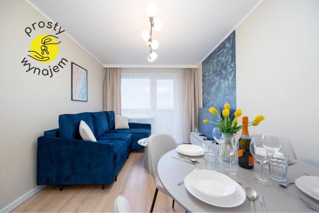 a living room with a blue couch and a table at Apartament Baltic Panorama ProstyWynajem Parking in Zaspa