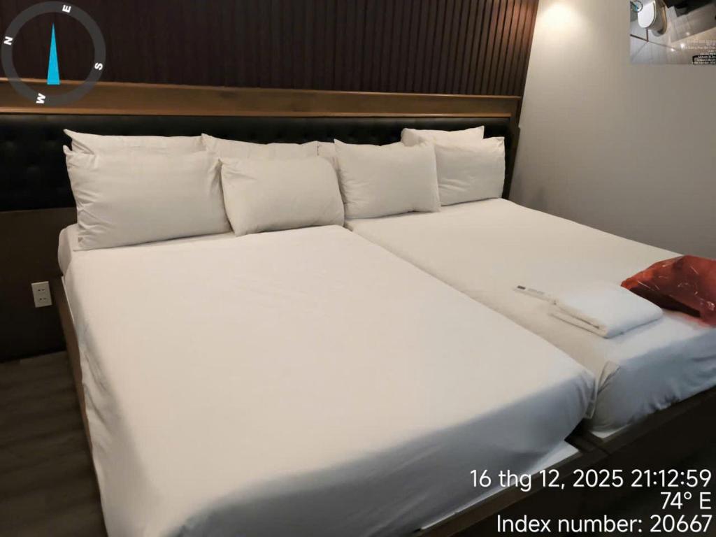 een groot bed met witte lakens en kussens bij shen hotel8 in Ho Chi Minh-stad