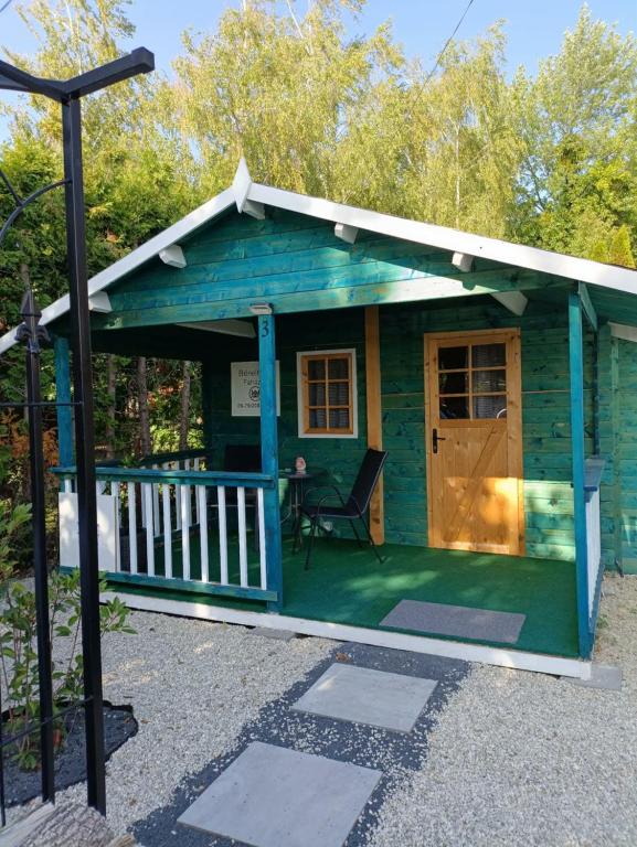 een blauw huis met een veranda en een stoel bij Fenyőházak in Buzsák