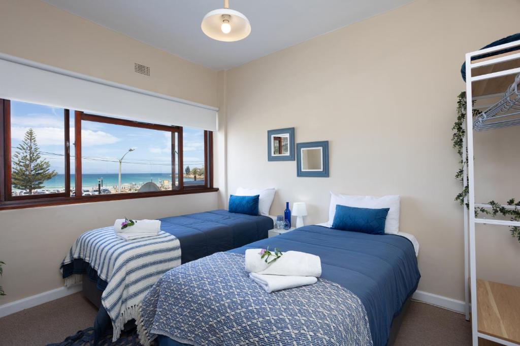 2 camas azules en una habitación con ventana en Beach Front Retreat in Fish Hoek, en Fish Hoek