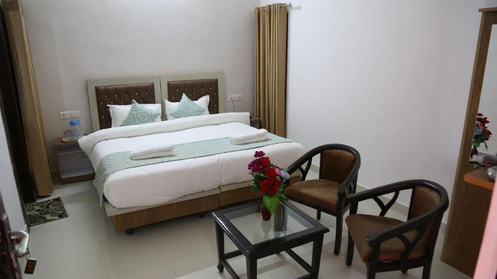 a bedroom with a bed with two chairs and a table at Hotel Yog Tapovan in Rishīkesh