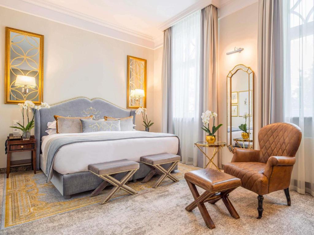 a bedroom with a king sized bed and a chair at Bachleda Luxury Hotel Kraków - MGallery Collection in Kraków