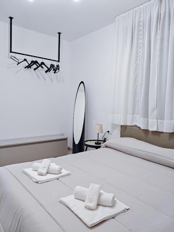 a white bed with two towels and a mirror at Dimora del Centro in Marsala