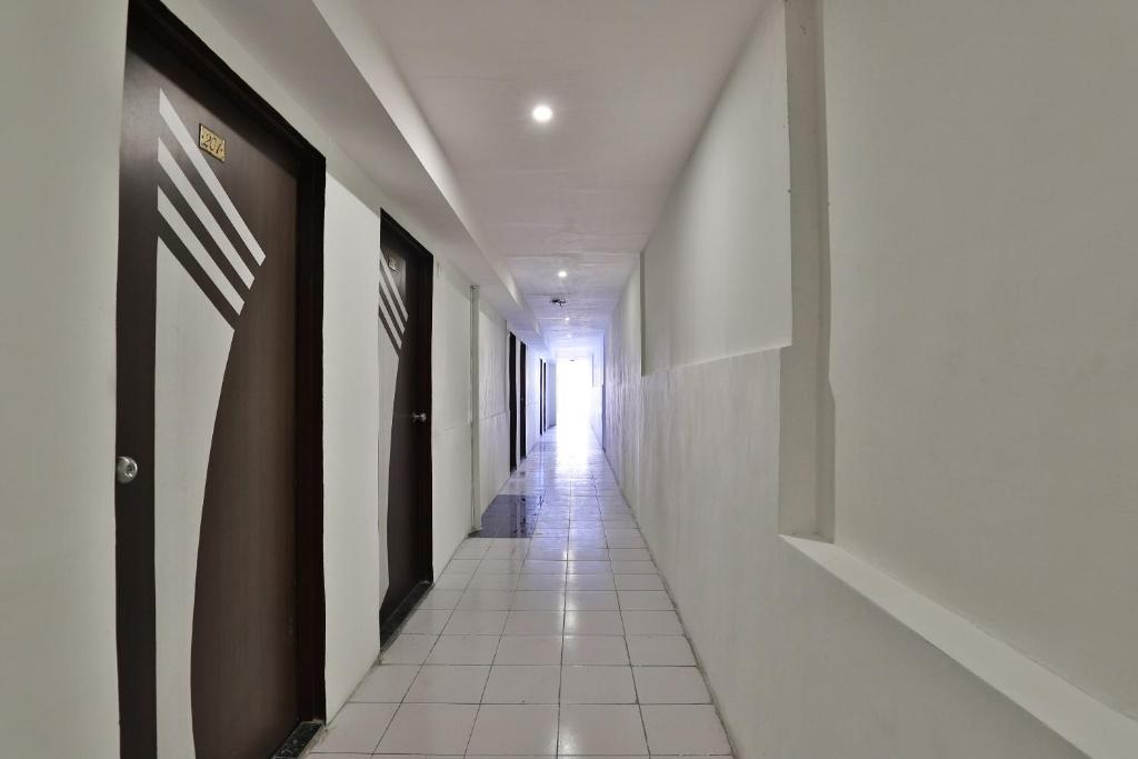 einen langen Flur mit weißen Wänden und weißem Fliesenboden in der Unterkunft Hotel O Mayura in Ankleshwar