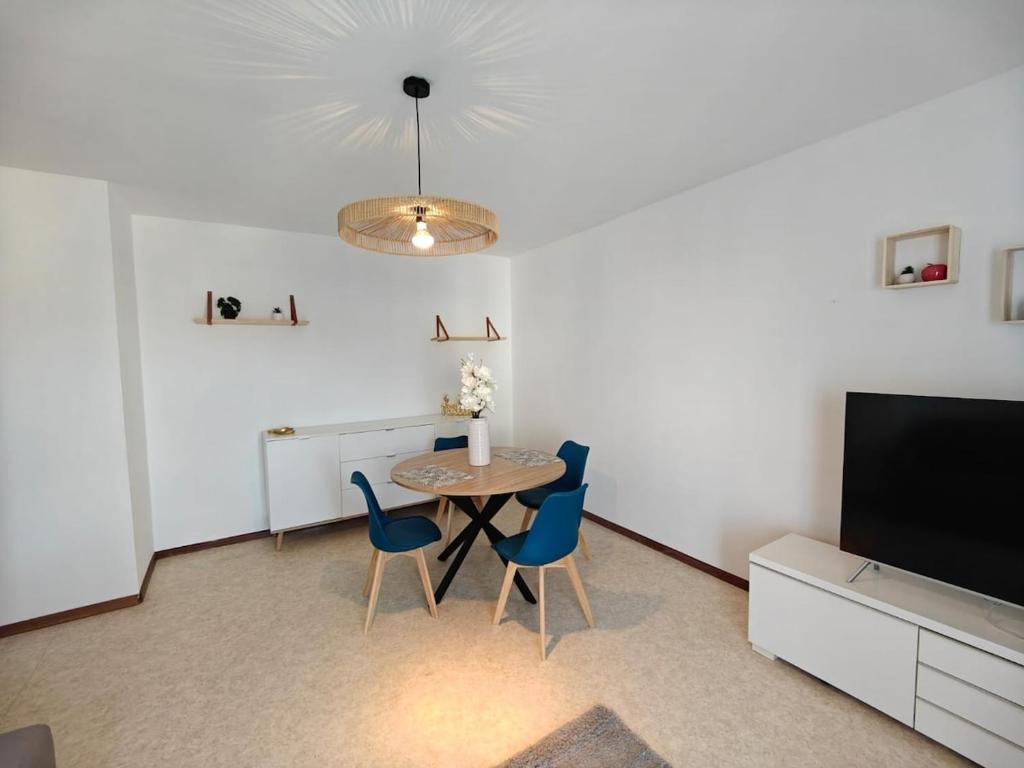 een eetkamer met een tafel, stoelen en een televisie bij F2 cozy centre ville proche bale et tram in Saint-Louis