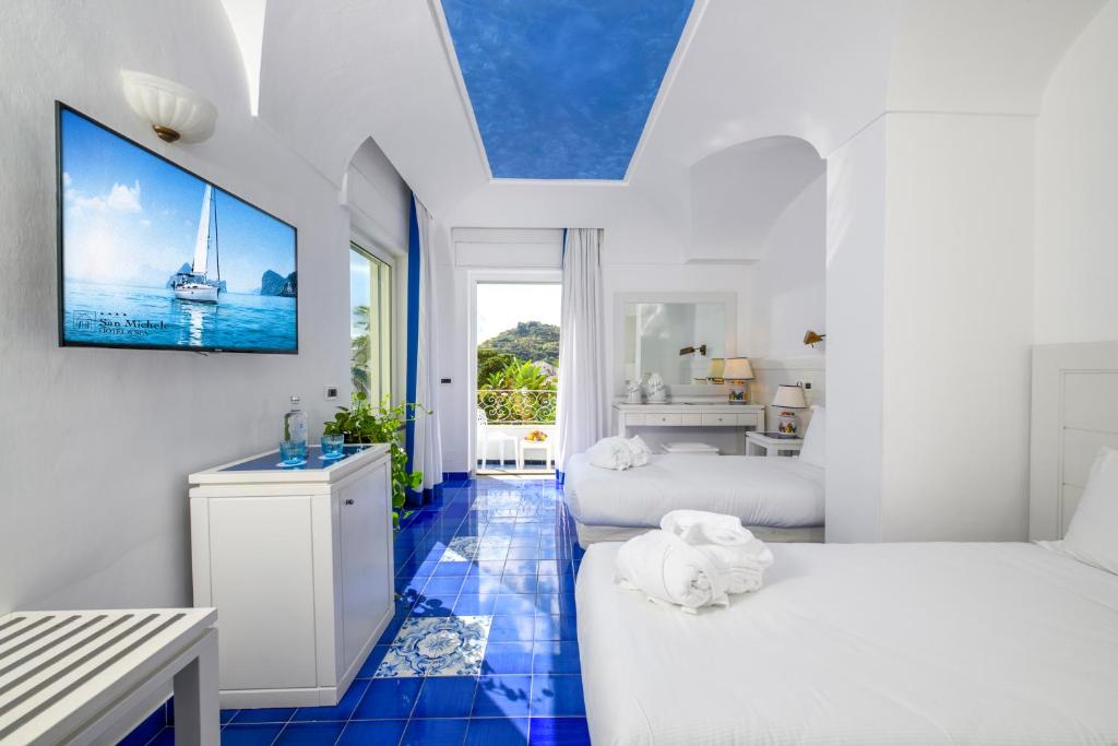 a white room with two beds and a tv on the wall at Hotel Terme San Michele & SPA, WorldHotels Distinctive in Ischia