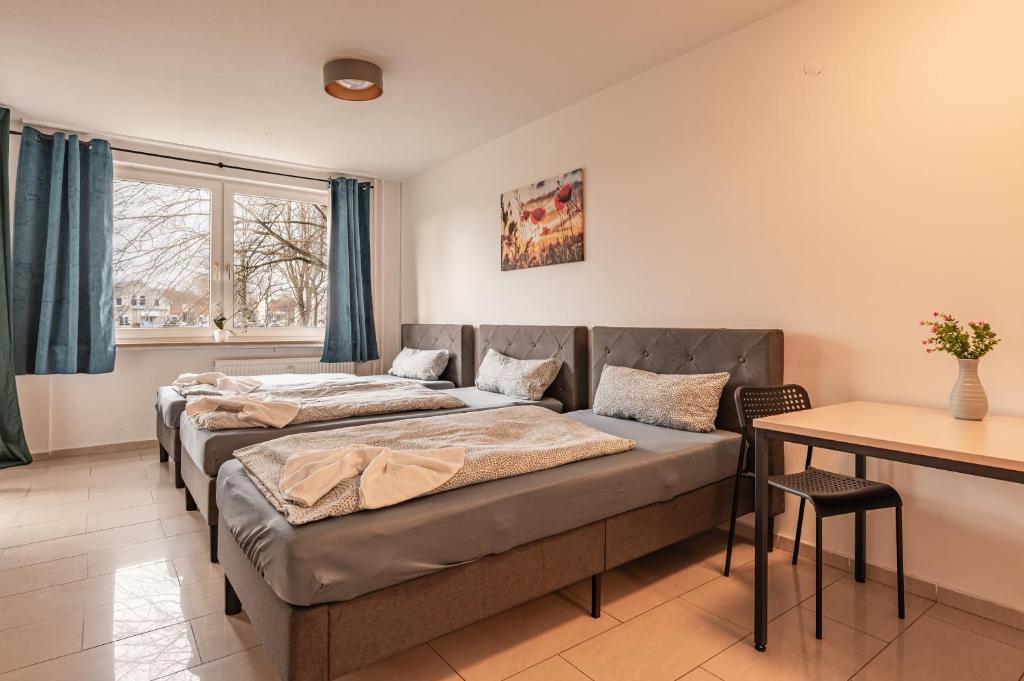2 Betten in einem Zimmer mit einem Tisch und einem Schreibtisch in der Unterkunft MK Apartments Delmenhorst nähe Bremen 3 in Delmenhorst