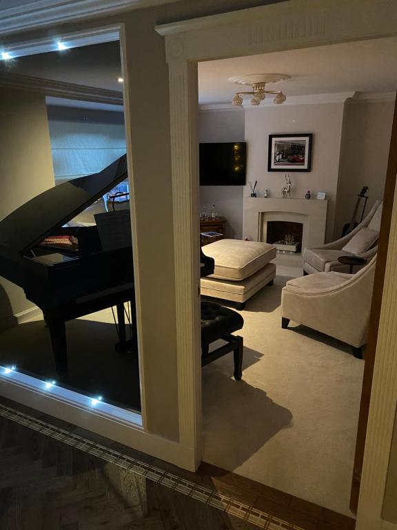 a room with a living room with a piano and a living room with a couch at Woodhead view in Kirkintilloch