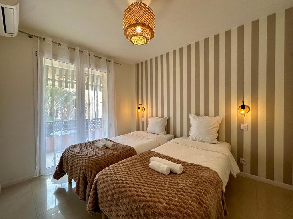 twee bedden in een kamer met gestreepte muren bij Palais du SOLEIL MONACO Terrasse & Parking in Beausoleil