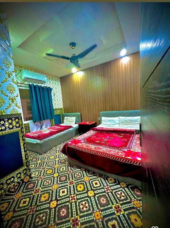 a bedroom with two beds and a mirror in it at AL AQSA SUiTES Guest House Islamabad in Islamabad