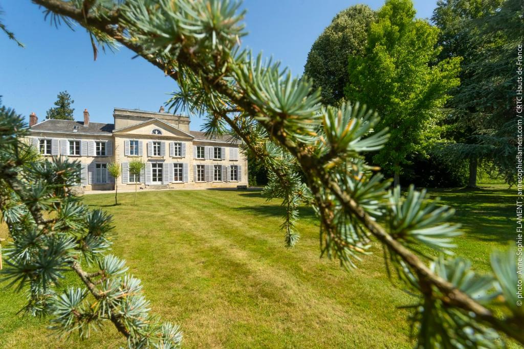 een afbeelding van een groot huis, gezien door een boom bij Château de Luzières in Conty