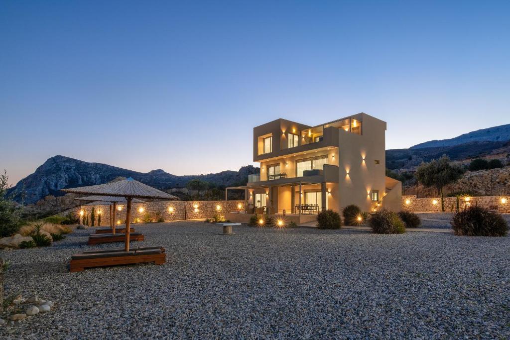 een groot huis met een verlichte tuin 's nachts bij Aquamarine Luxury Suites - Stegna in Archangelos