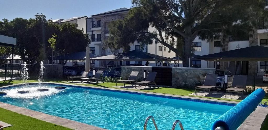 a large swimming pool with a fountain in a yard at The Jade, Somerset West in Strand