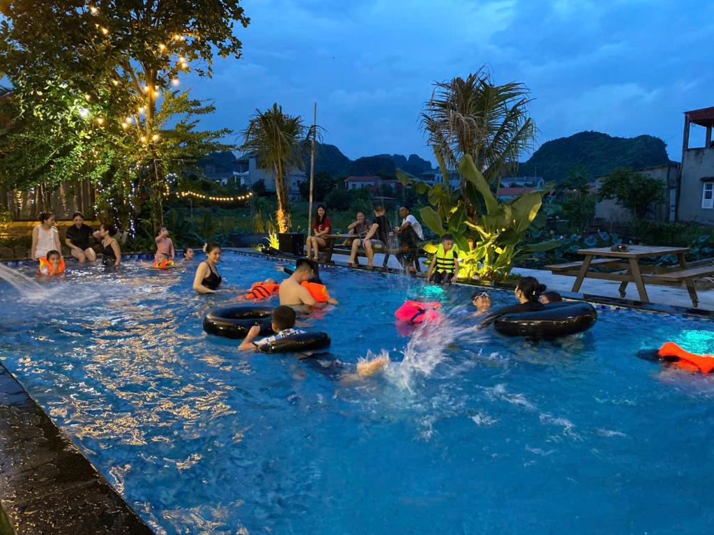 eine Gruppe von Menschen, die nachts im Schwimmbad spielen in der Unterkunft Ninh Binh Royal Bungalow in Xuân Sơn