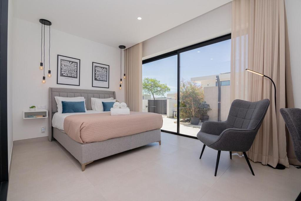een slaapkamer met een bed en een stoel en een groot raam bij Sirius House in Guia