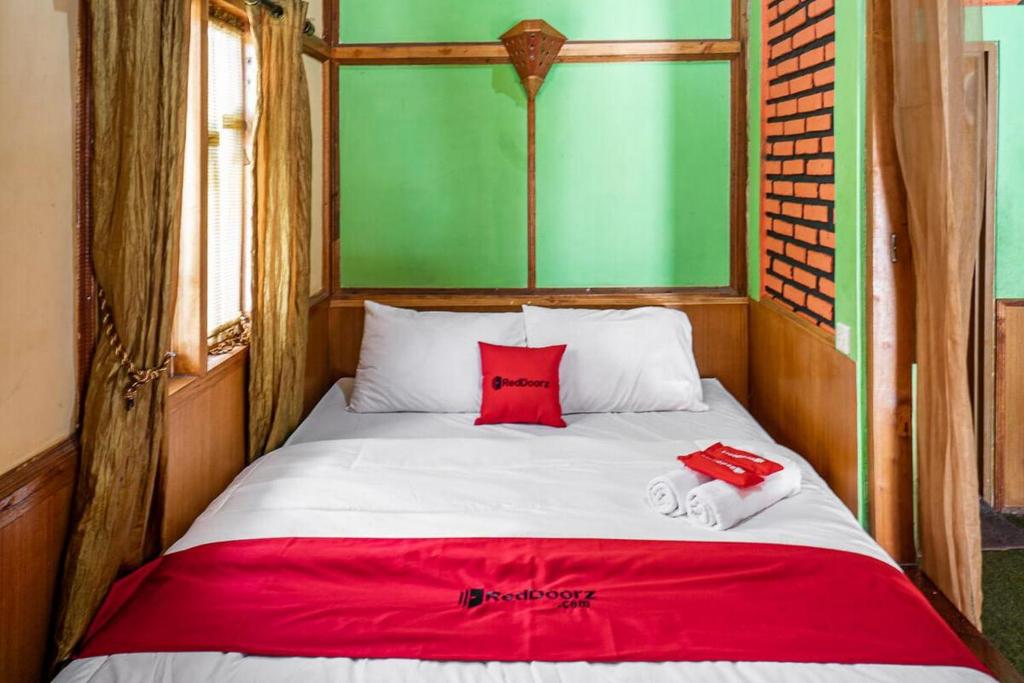 een bed met twee rode kussens erop bij RedDoorz near Kawah Putih Ciwidey in Bandung