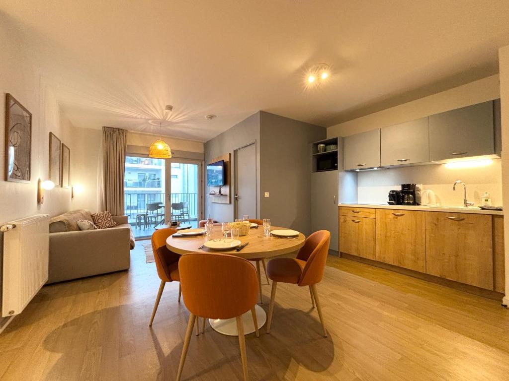 eine Küche und ein Wohnzimmer mit Tisch und Stühlen in der Unterkunft L'Oranger bleu in Royan
