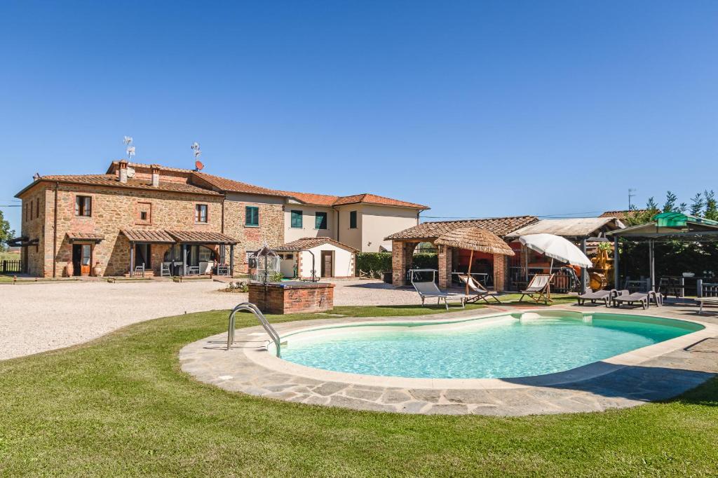 a swimming pool in front of a large house at Il Podere - Rustic Charm in Tuscany in Monte San Savino