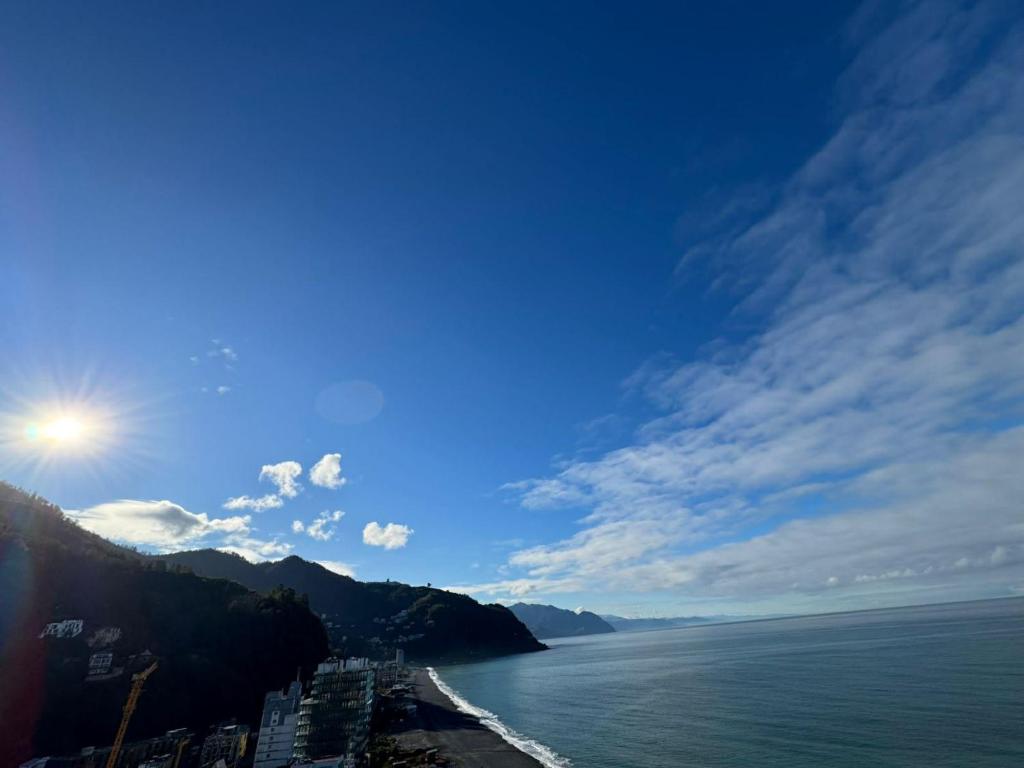 a view of the ocean with a city and the sun at Zura's Sea View Apartments in Gonio