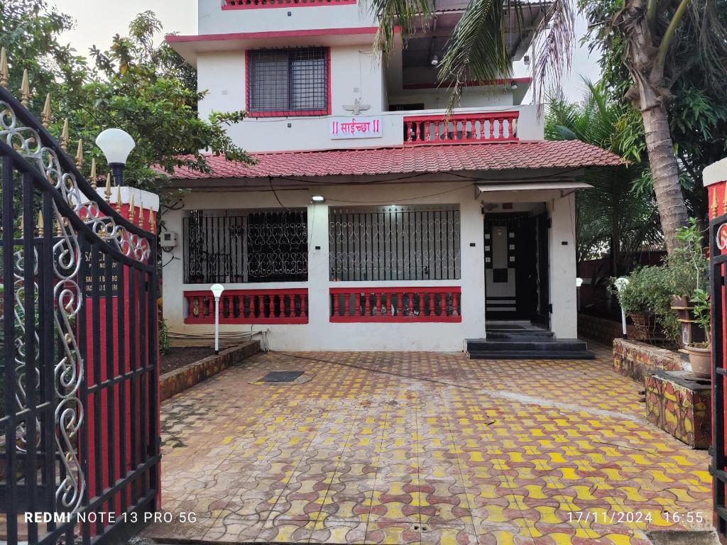 ein weißes Haus mit einem roten Tor und einem Innenhof in der Unterkunft Om sai villa in Neral