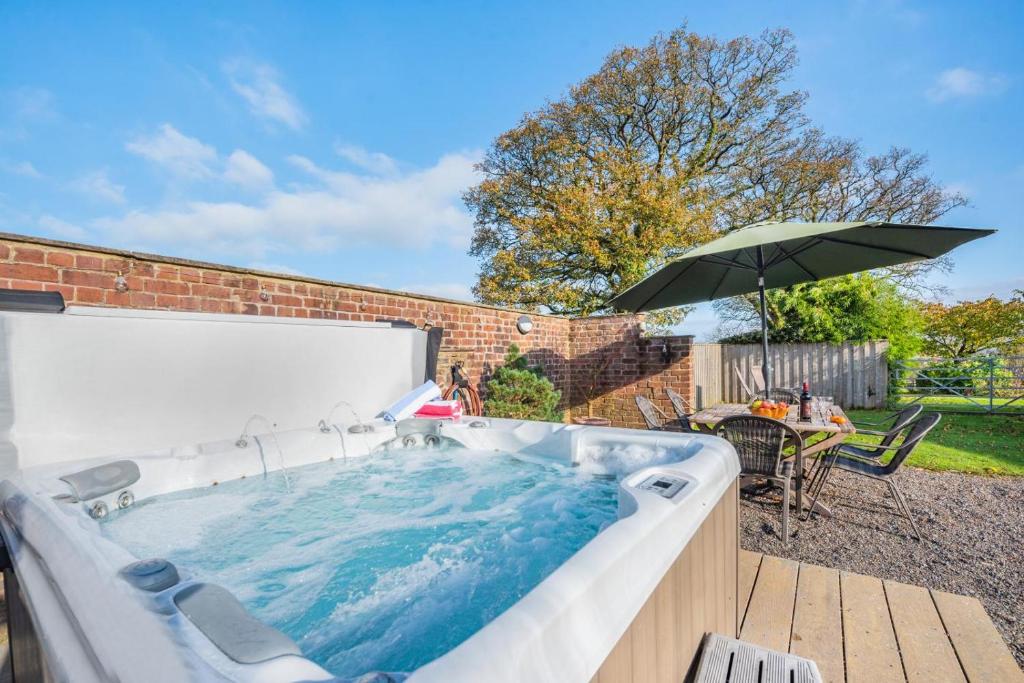 a hot tub in a backyard with an umbrella at 3 Bed in Llanddarog oc-p30291 in Llanddarog