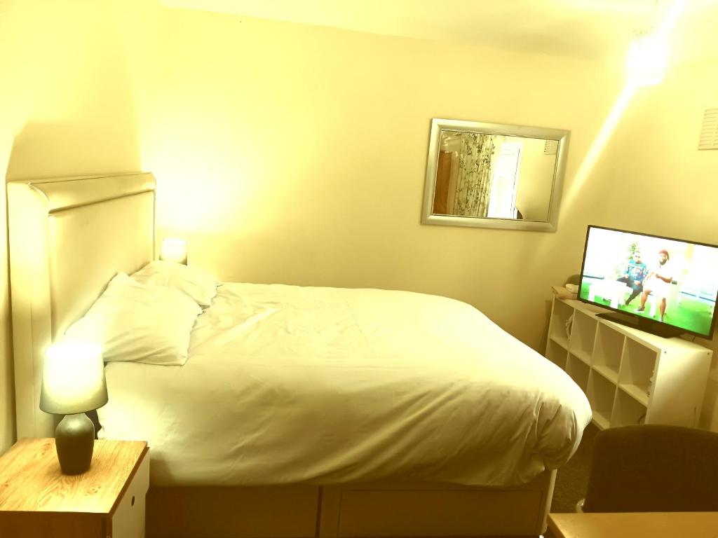 Un dormitorio con una cama blanca y un televisor. en High class accommodations 10, en Little Hulton