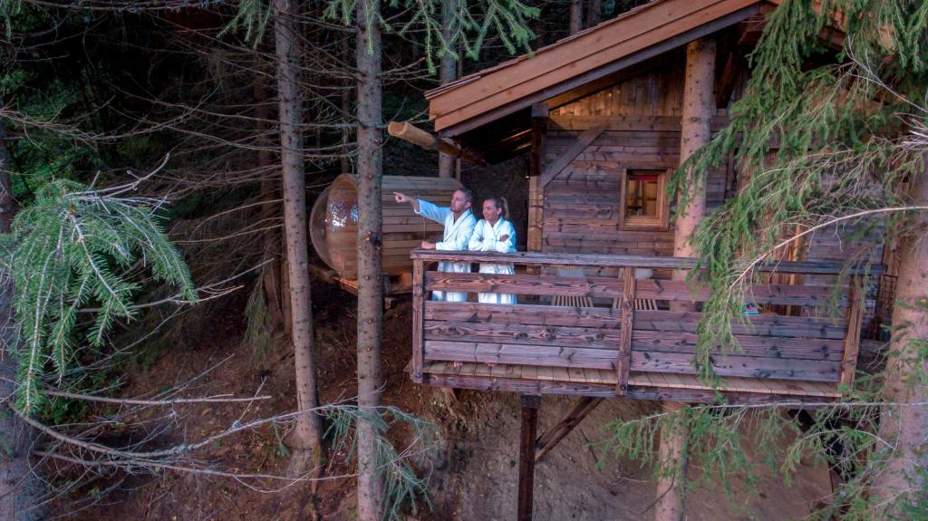 two people standing on the balcony of a tree house at Cabane entre terre et ciel in Saint-Nicolas-la-Chapelle