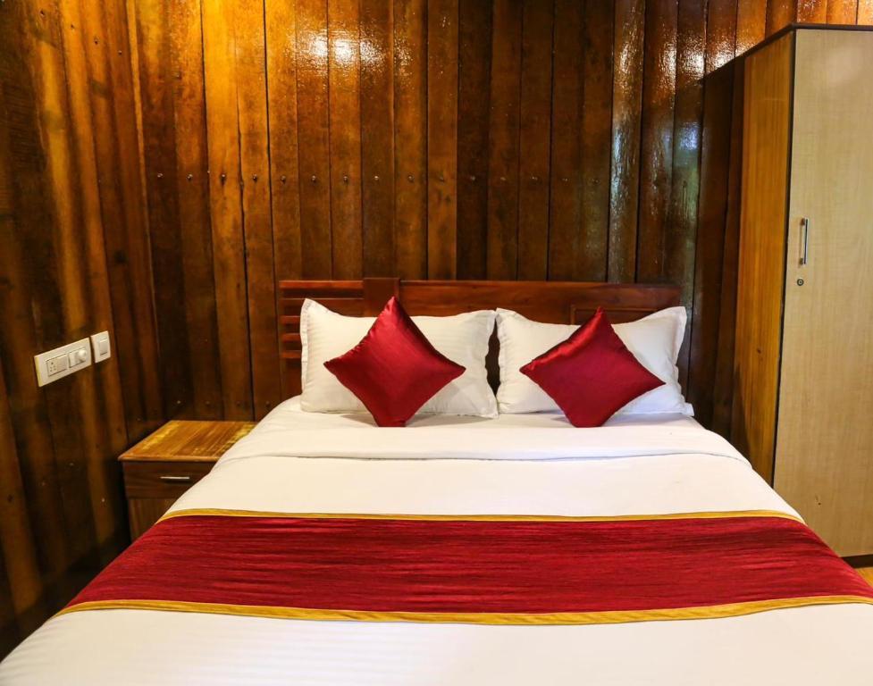 ein Schlafzimmer mit einem Bett mit roten Kissen in der Unterkunft DJ River Meadows By Let's Inn in Panamaram
