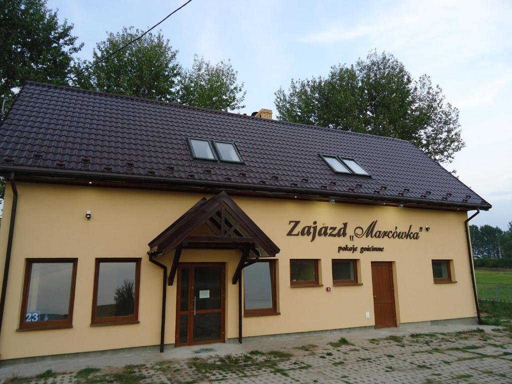a building with a black roof at zajazd ''Marcówka" in Bakałarzewo