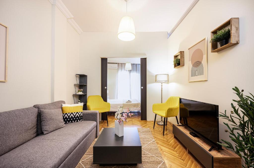 un soggiorno con divano grigio e sedie gialle di Houseloft Bianca Vision a Salonicco