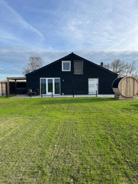 a black house with a large yard in front of it at B&B de Landstreek in Hulten